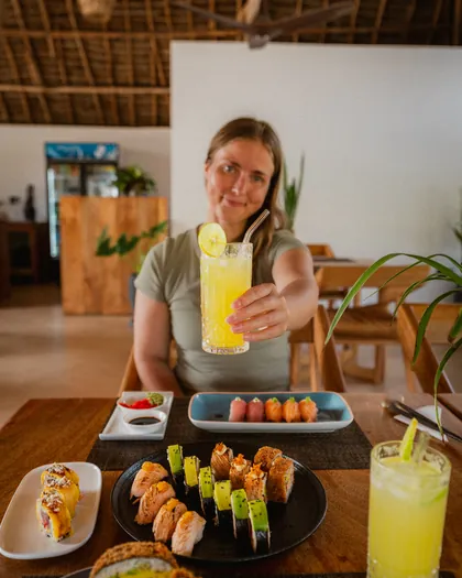 A guest raising her glass over sushi at KAMI