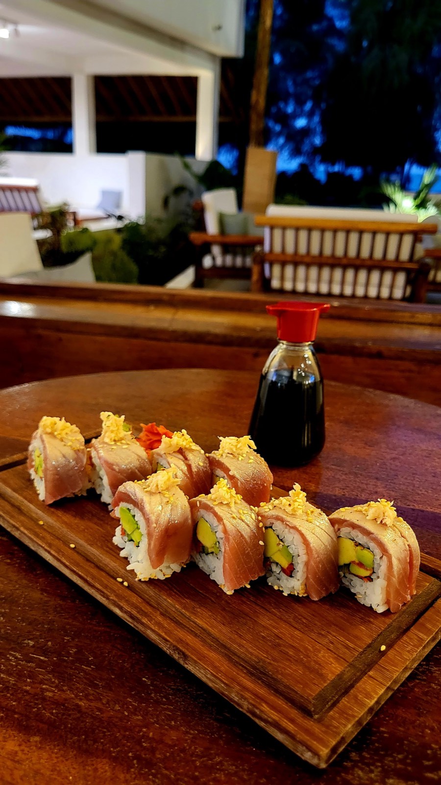Roll con tonno e sesamo accanto a una bottiglia di soia al tramonto in terrazza